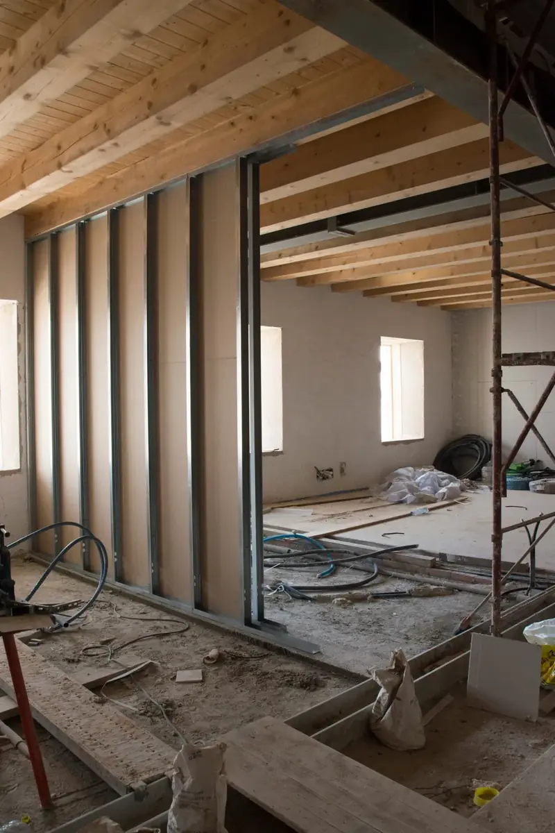 Parete divisoria in costruzione: orditura metallica con le prime lastre di cartongesso sotto un soffitto in travi di legno